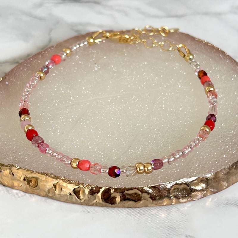 Flot armbånd med perler i et lækkert, rødt mix. Smykket er håndlavet med tjekkisk krystal, som er kendt for sin fine kvalitet. Kan du lide kræs, så er det nu, du skal slå til!